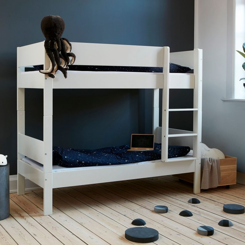 A white colored bunk bed with safety rail